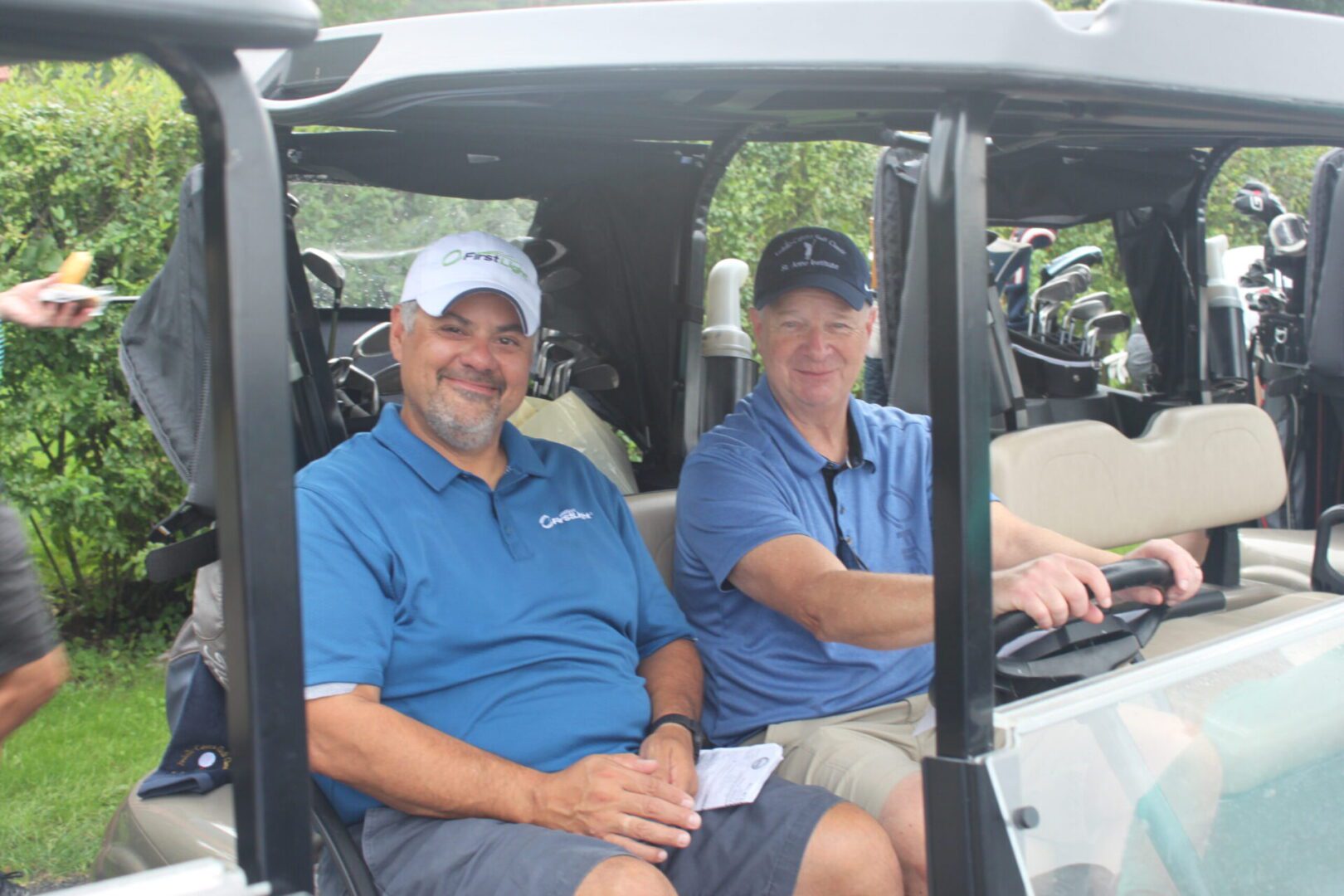 Two men sitting in the back of a golf cart.