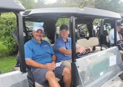 Two men sitting in golf carts at a golf tournament.