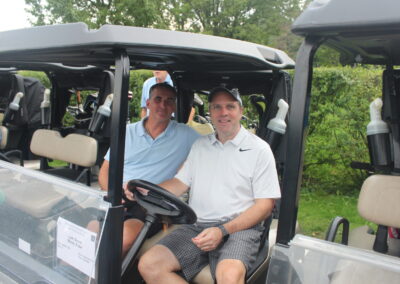 Two men sitting in the back of a golf cart.