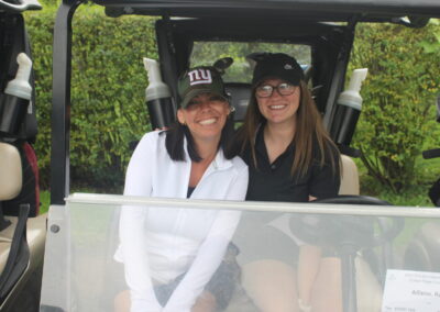 Two women sitting in a golf cart.