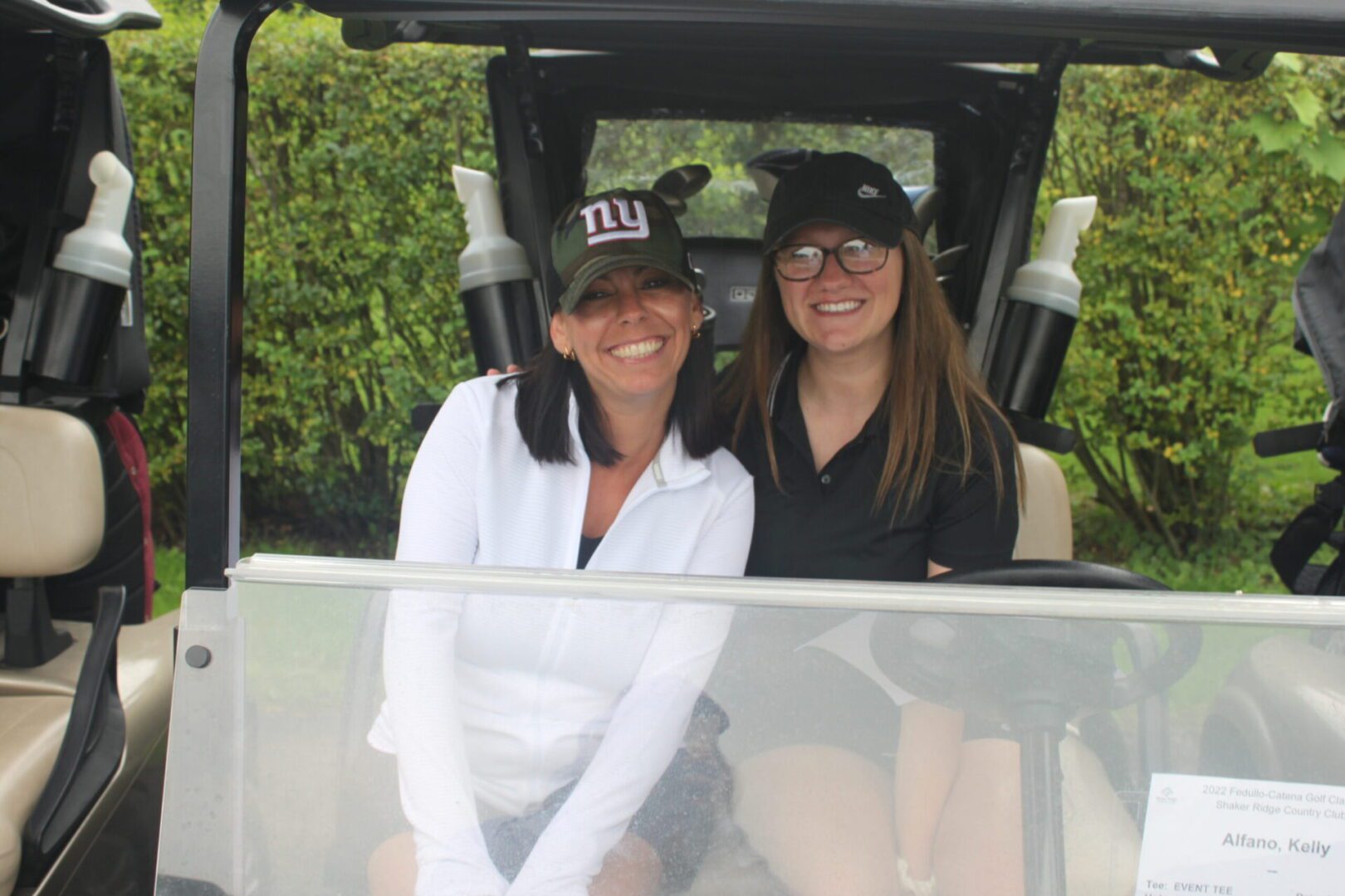 Two women sitting in a golf cart.