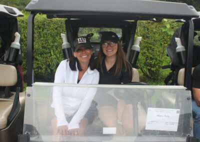 Two women posing for a photo in a golf cart.