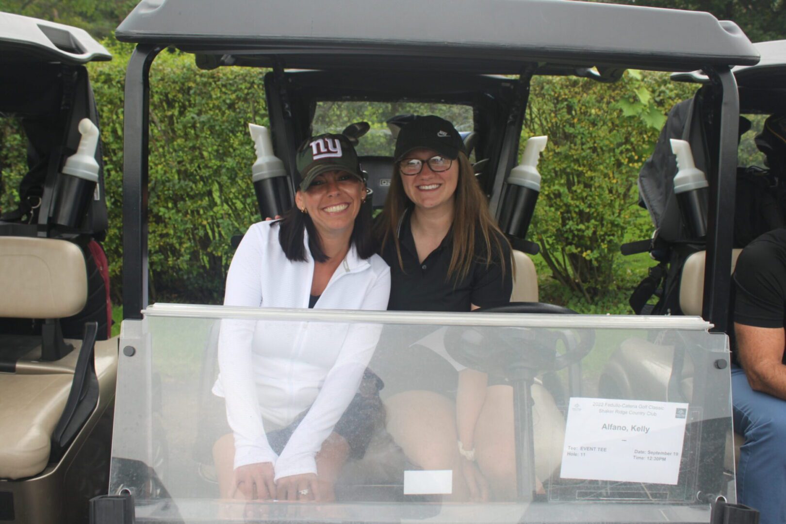 Two women posing for a photo in a golf cart.