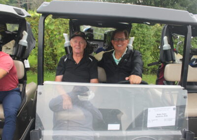 A group of men in golf carts smiling at the camera.