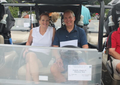 A man and woman sitting in a golf cart.