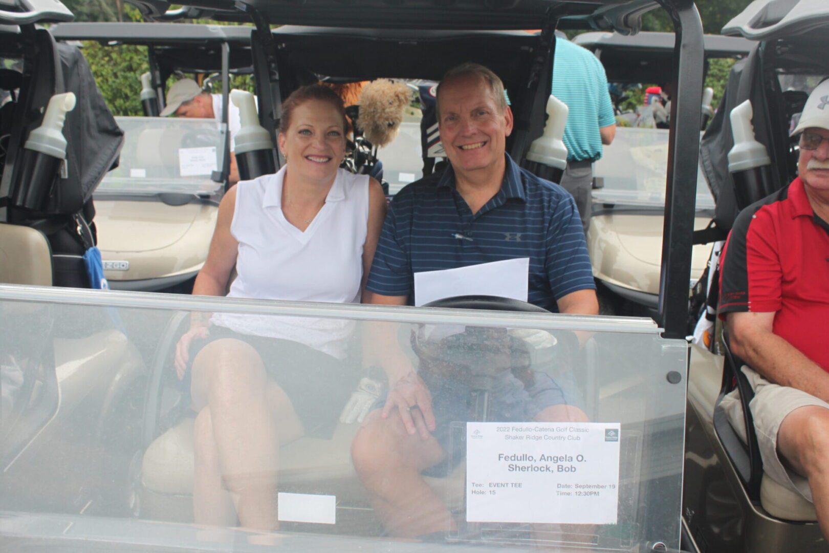 A man and woman sitting in a golf cart.