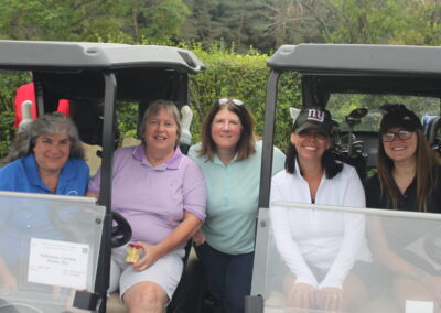 A group of women posing for a picture in a golf cart.