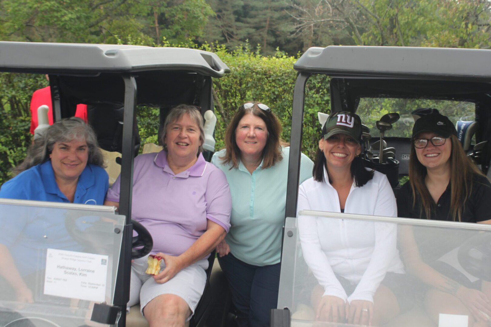 A group of women posing for a picture in a golf cart.