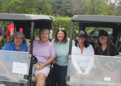 A group of women sitting in a golf cart.