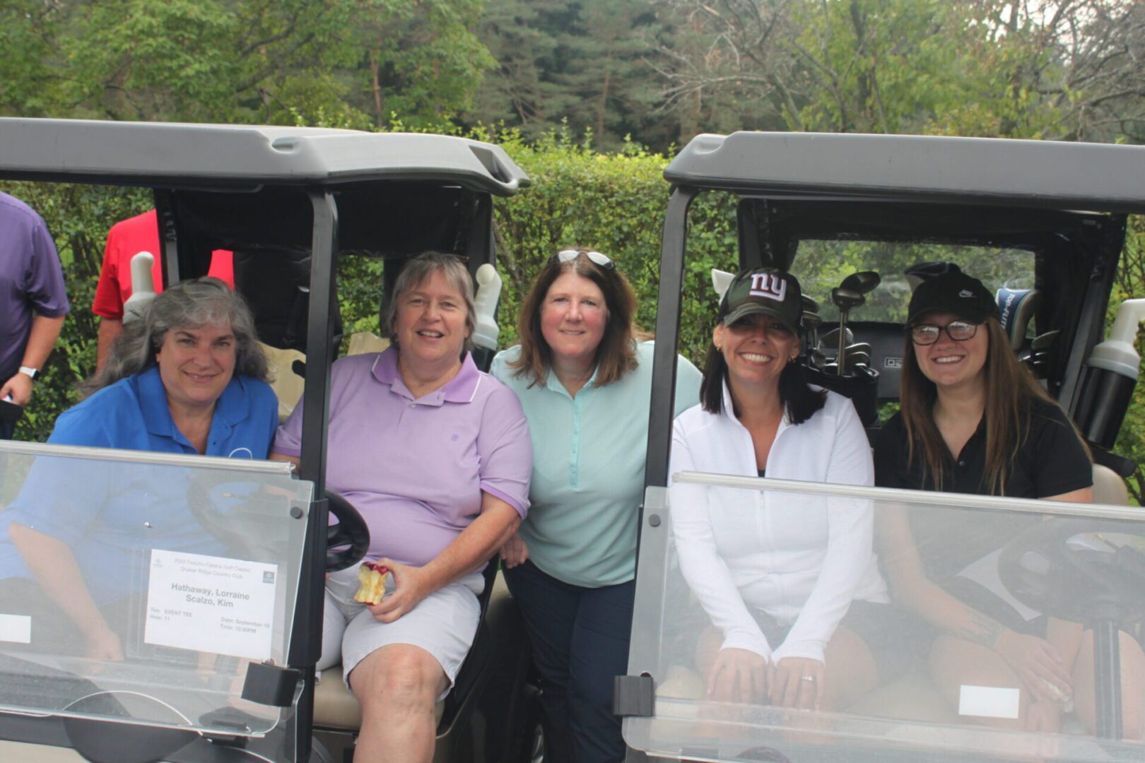 A group of women sitting in a golf cart.