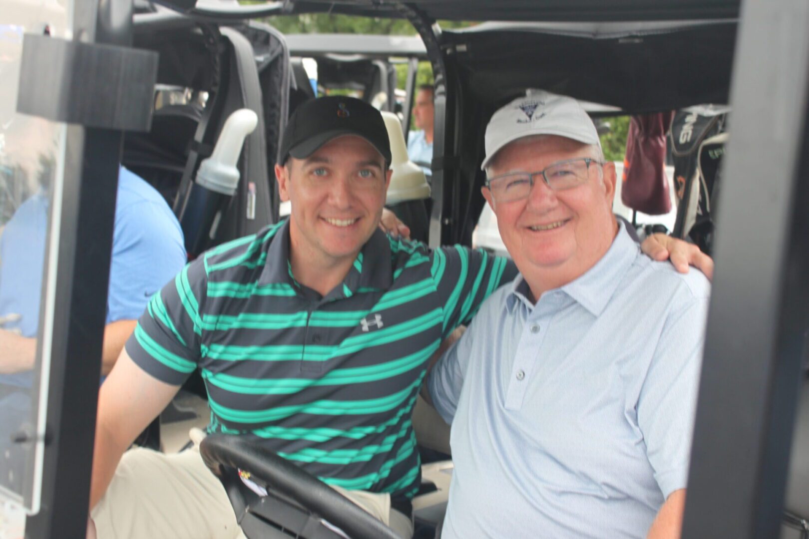 Two men sitting in a golf cart.