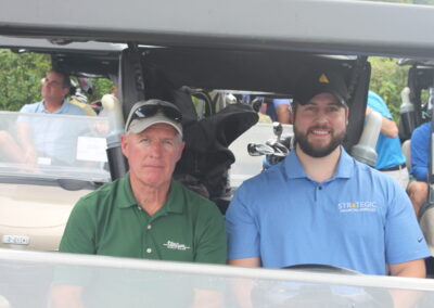 Two men sitting in the back of a golf cart.