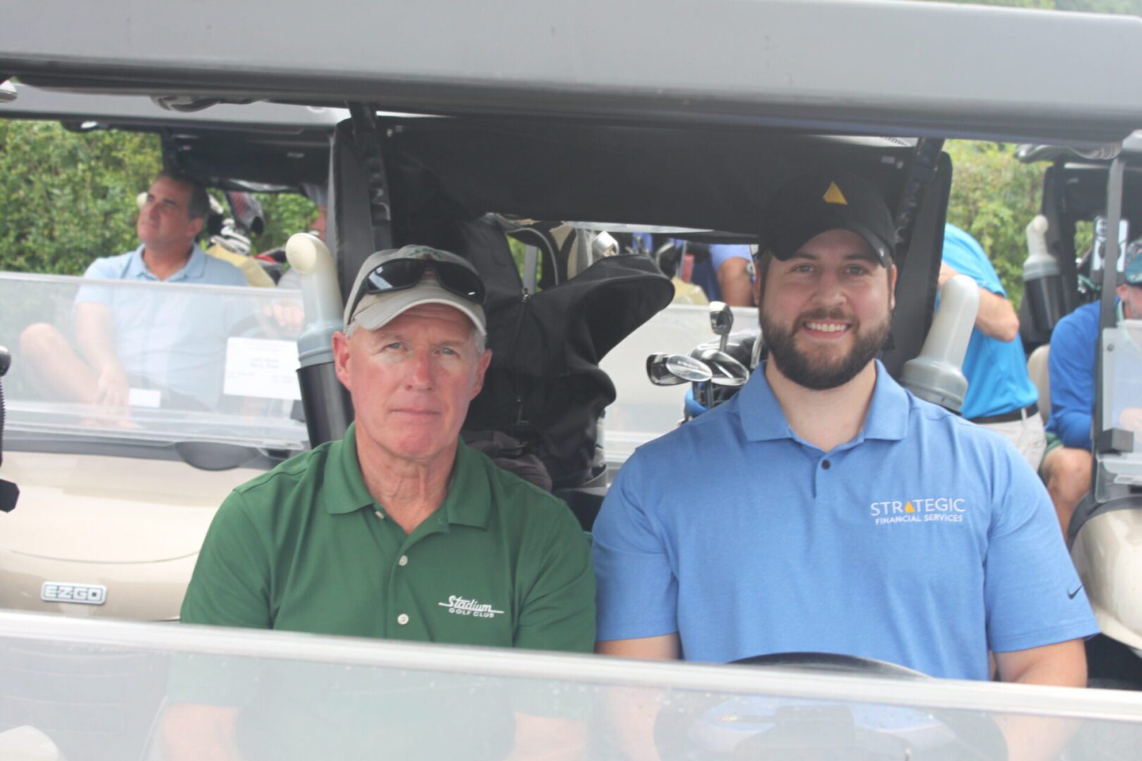 Two men sitting in the back of a golf cart.