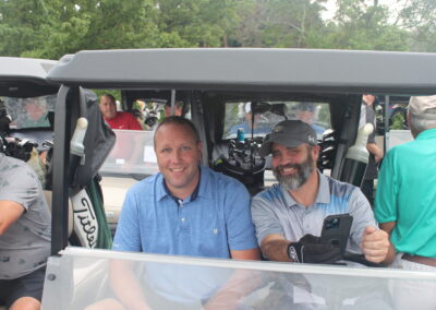 A group of men in a golf cart posing for a photo.