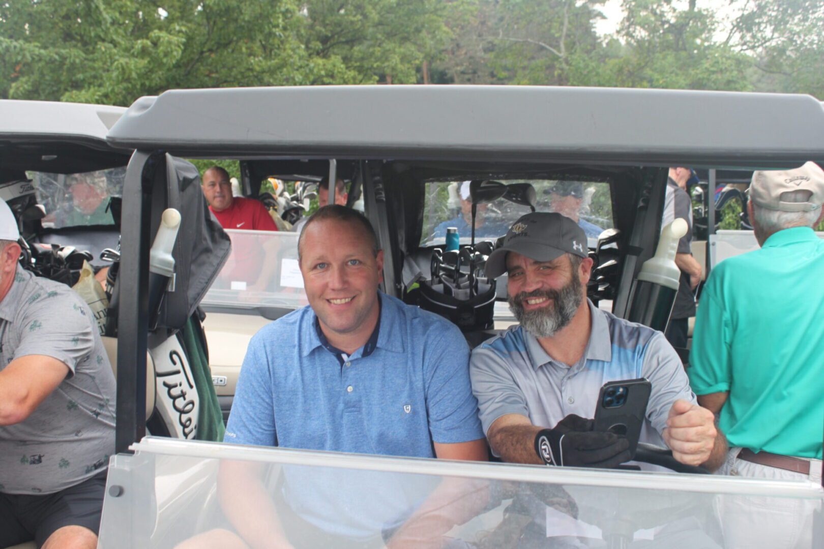 A group of men in a golf cart posing for a photo.