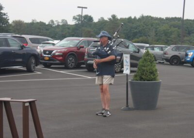 A man playing a bagpipe in a parking lot.