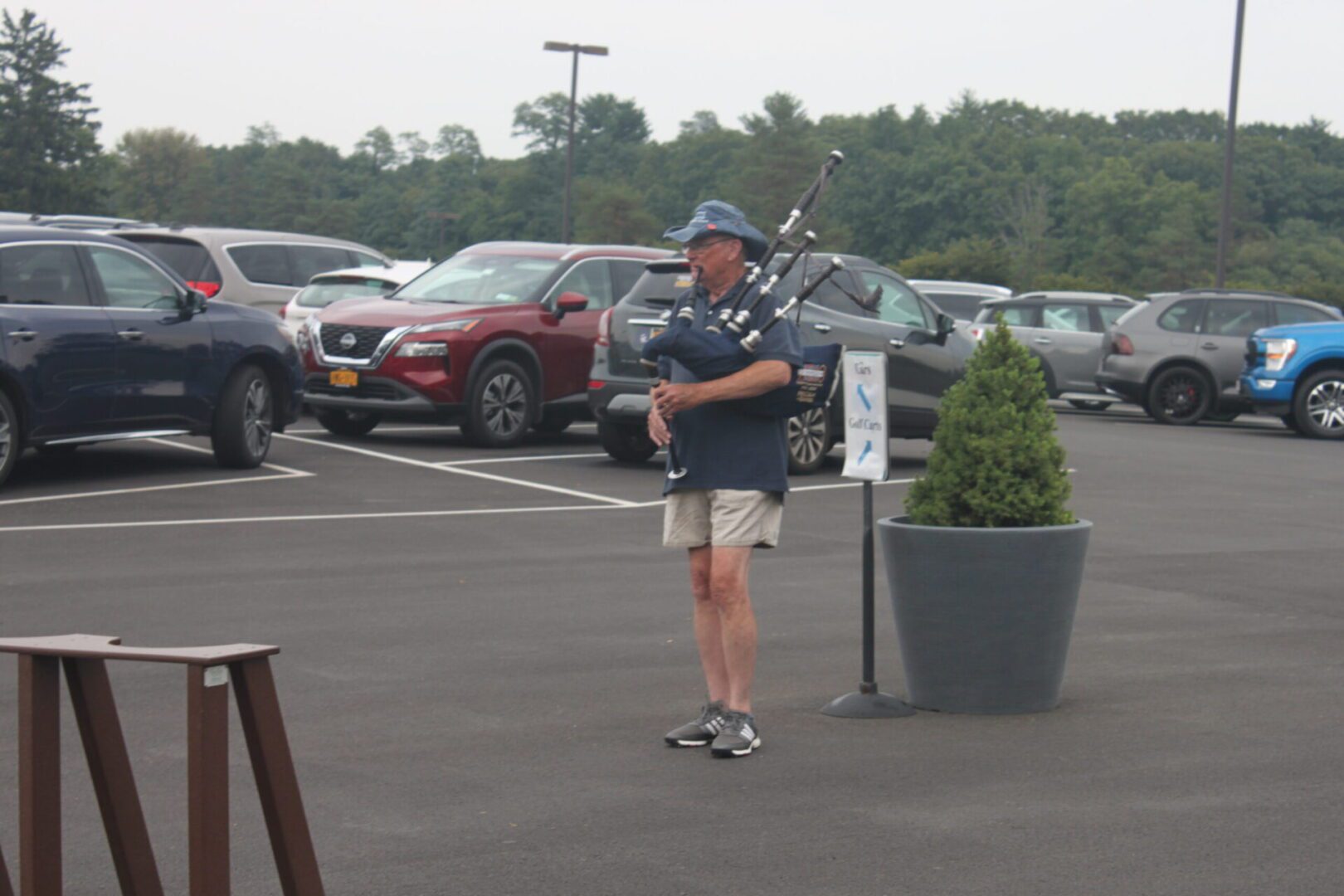 A man playing a bagpipe in a parking lot.