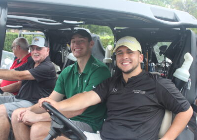 A group of men in a golf cart smiling.