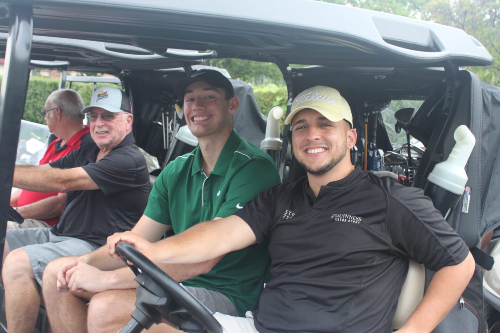 A group of men in a golf cart smiling.
