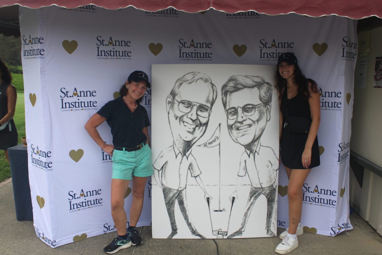 Two women standing next to a caricature of a man and a woman.