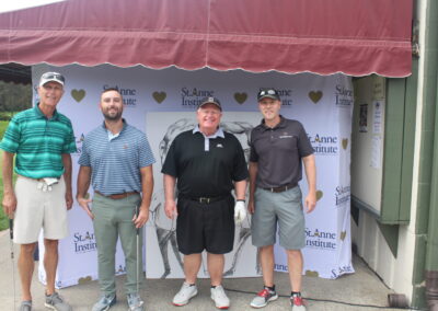 Four men posing for a photo in front of a tent.