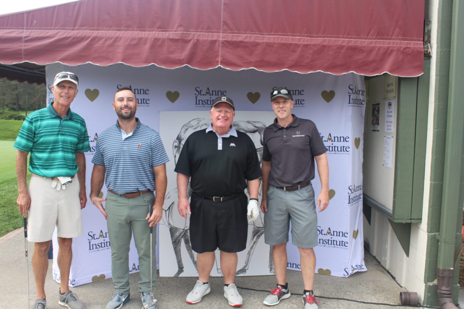 Four men posing for a photo in front of a tent.