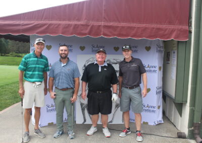 Four men posing for a photo in front of a tent.