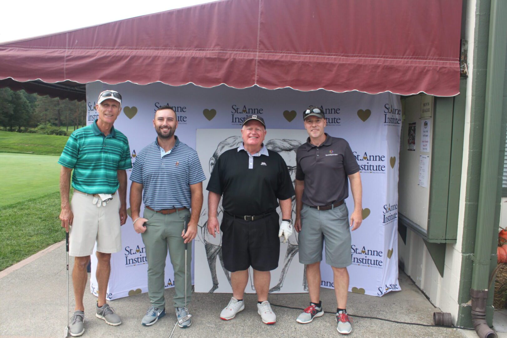 Four men posing for a photo in front of a tent.