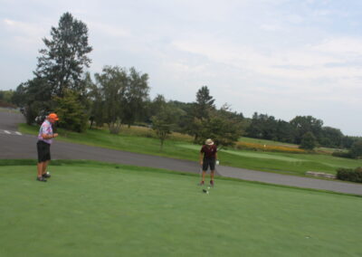 Two people standing on a green golf course.