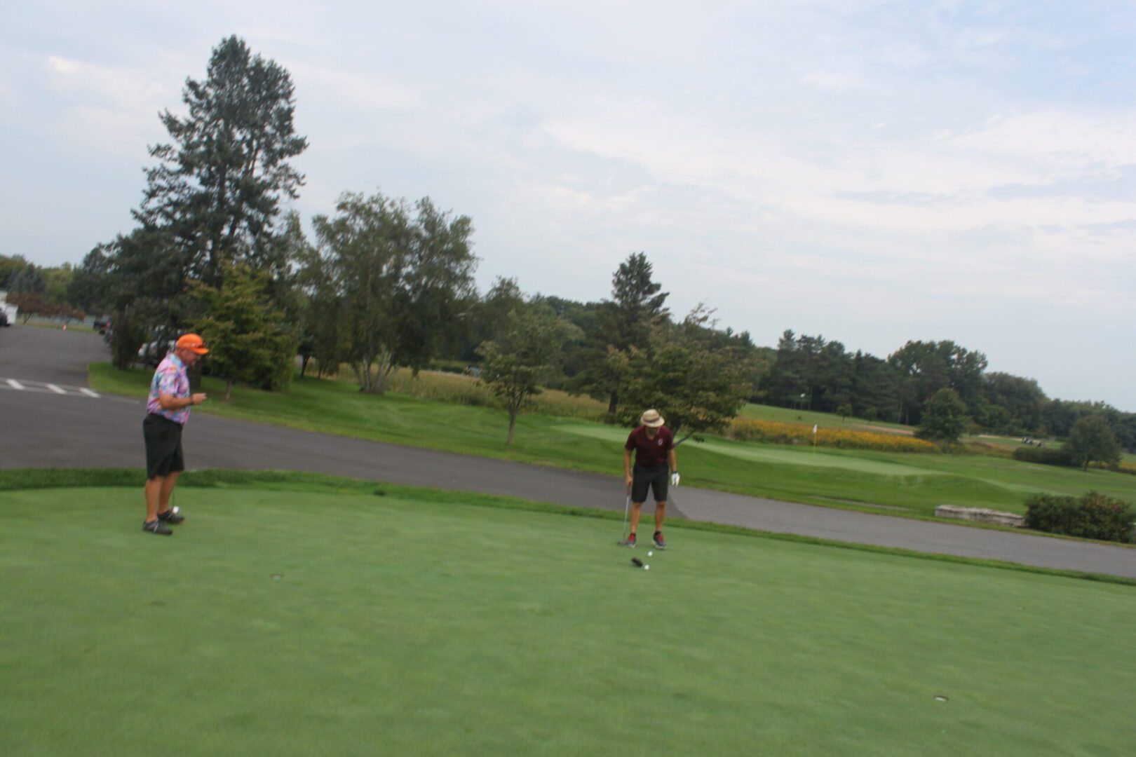 Two people standing on a green golf course.