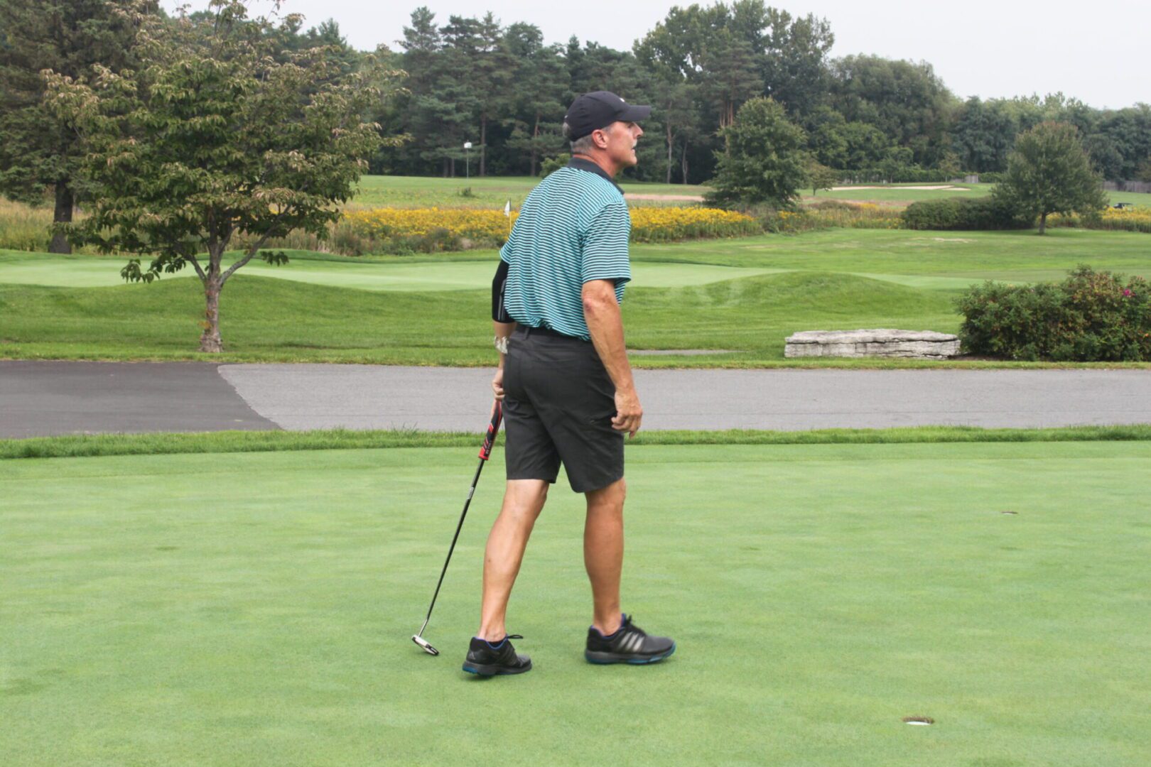 A man is standing on a golf course.