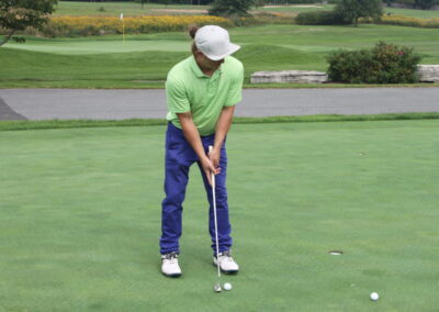 A man in a green shirt is putting on a golf course.