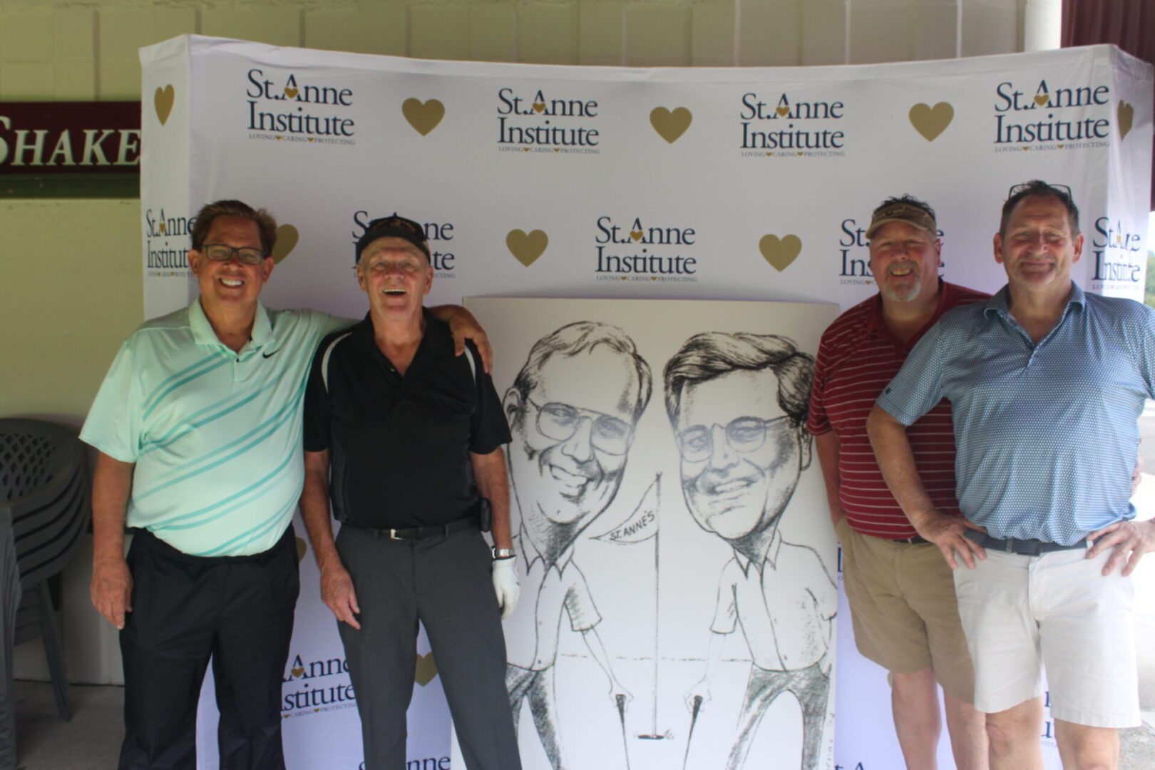 A group of men posing for a photo in front of a caricature.