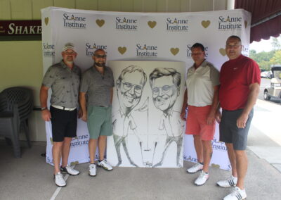 Four men posing for a photo with a caricature.