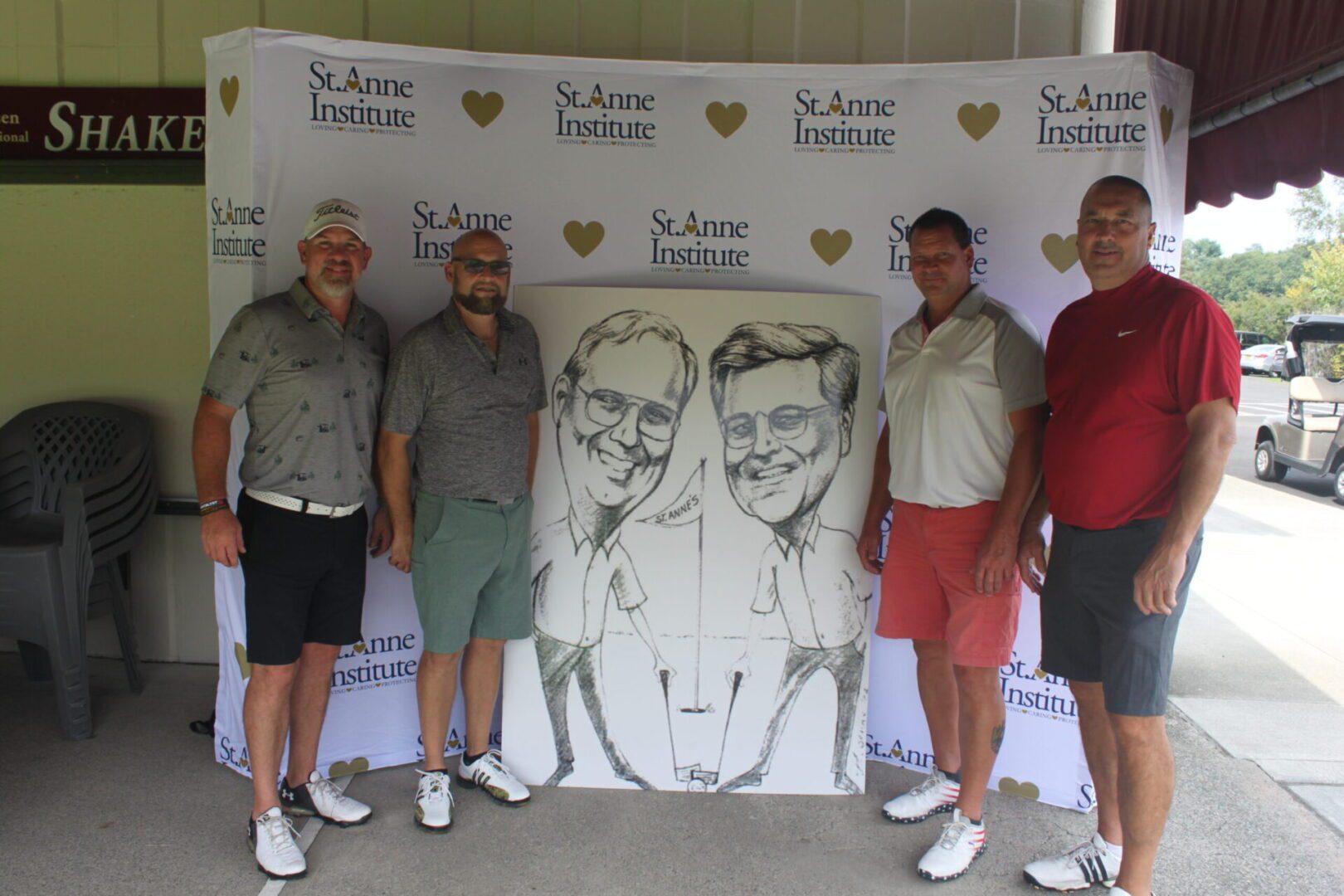 Four men posing for a photo with a caricature.