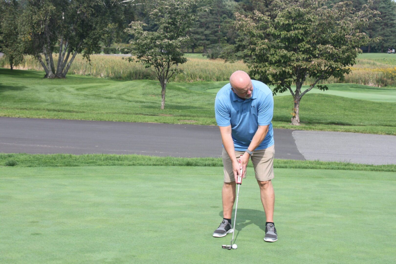 A man is putting a golf ball on a green.