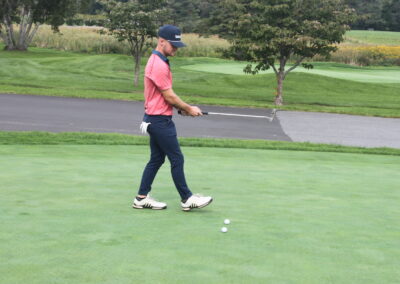 A man in a pink shirt is putting on a golf course.