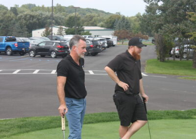 Two men standing next to each other on a golf course.