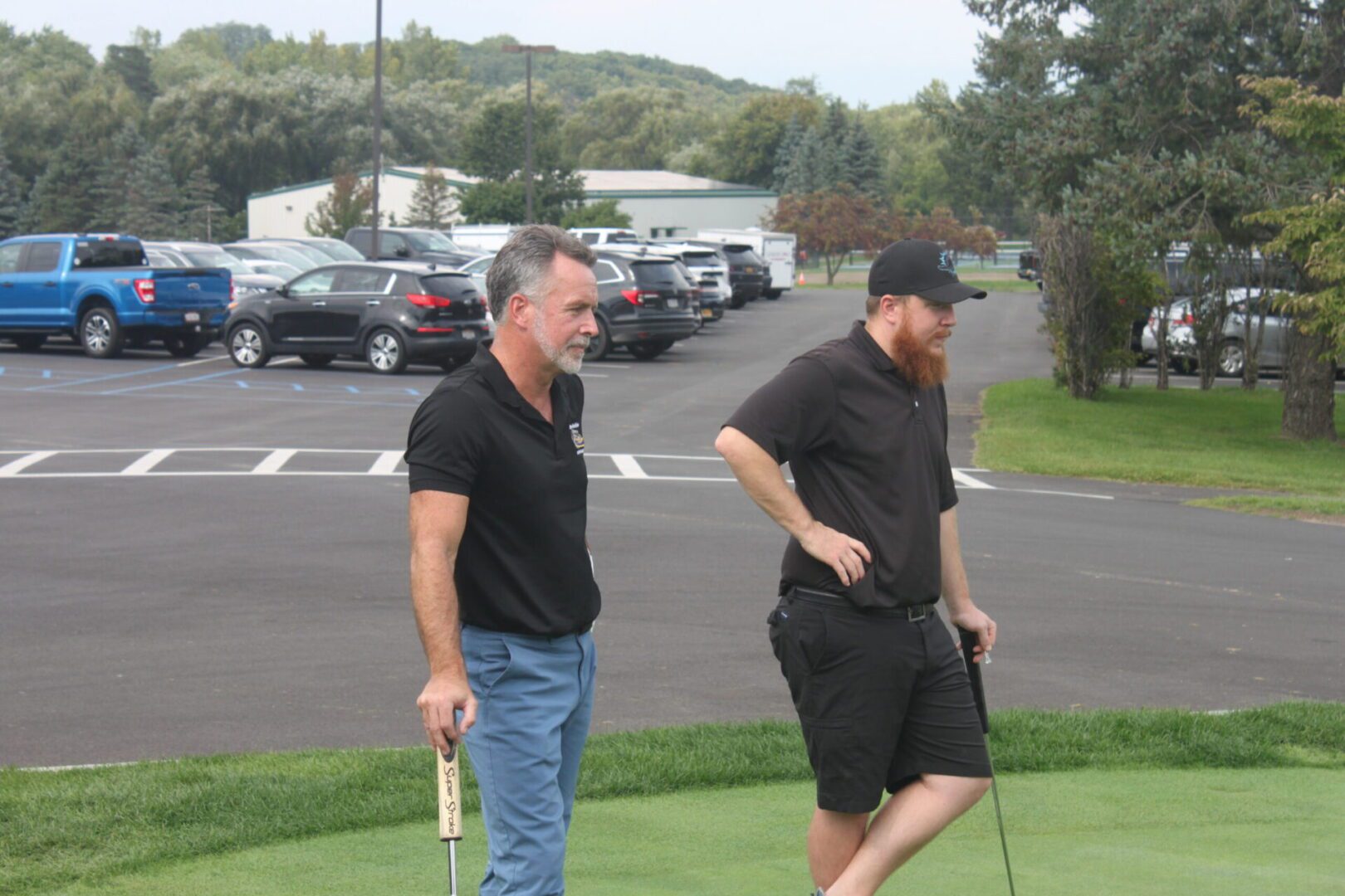 Two men standing next to each other on a golf course.