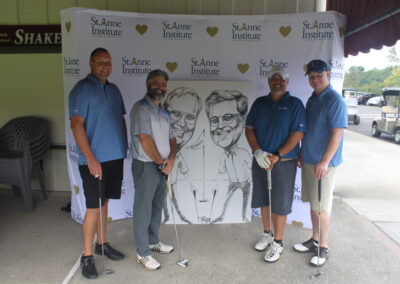 Four men posing for a photo with a golf caricature.