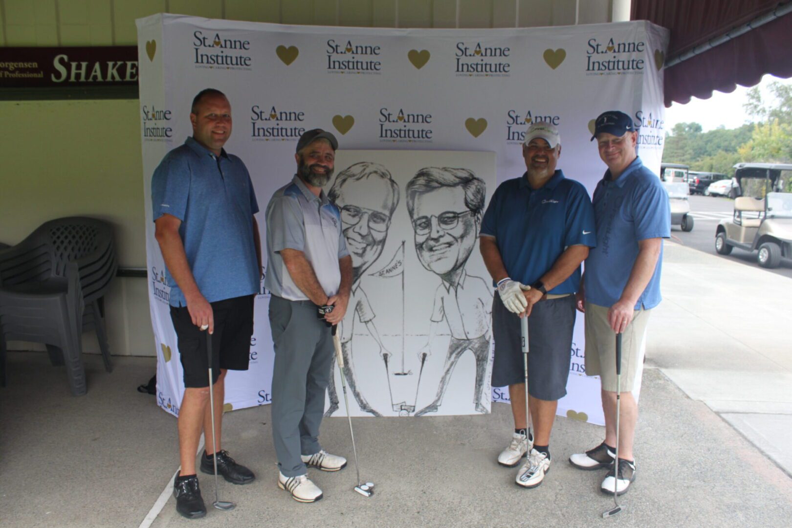 Four men posing for a photo with a golf caricature.