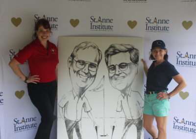 Two women standing next to a caricature.