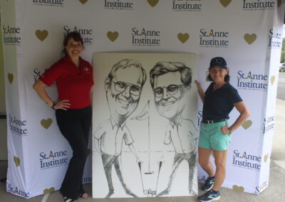 Two women standing next to a caricature of two men.