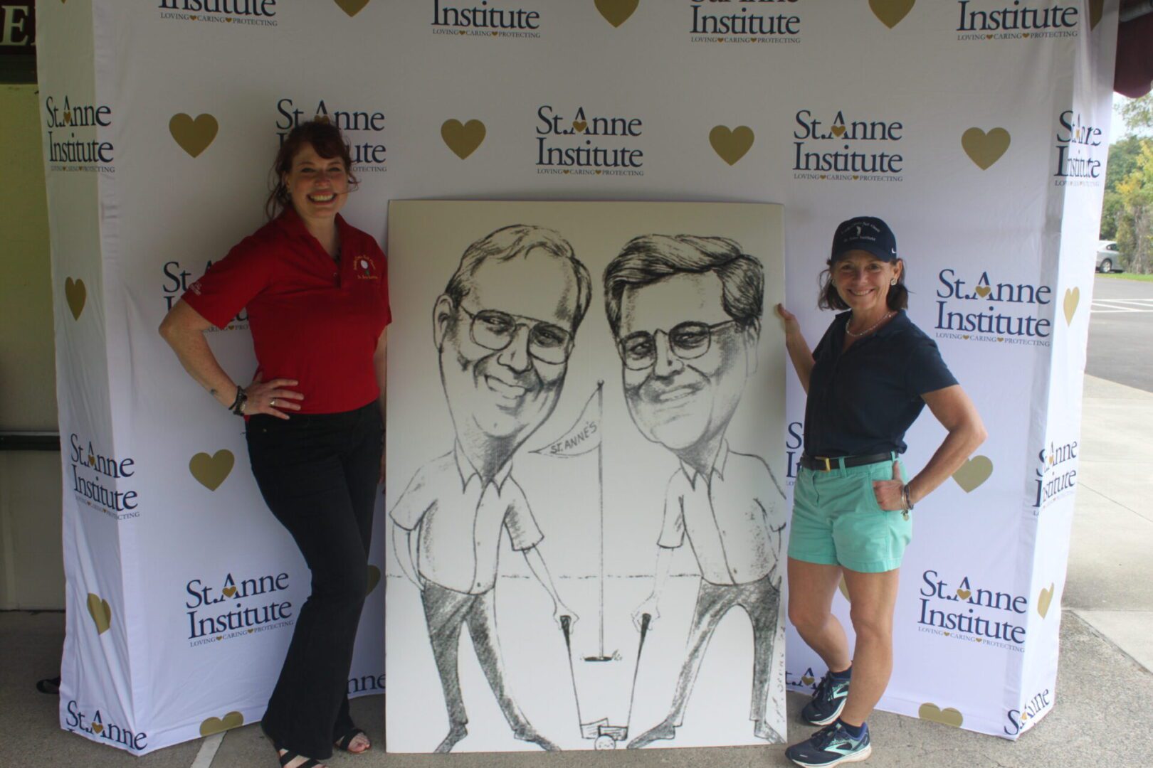 Two women standing next to a caricature of two men.