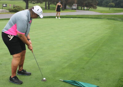 A woman is putting a golf ball on a green.