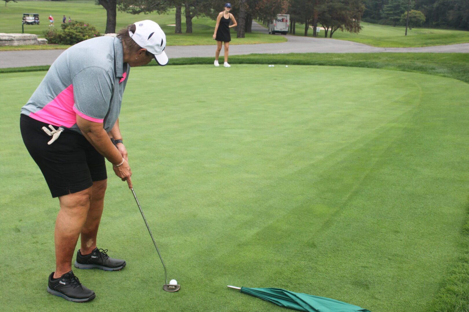 A woman is putting a golf ball on a green.