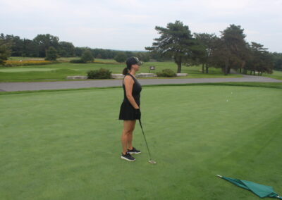 A woman is standing on a golf course.