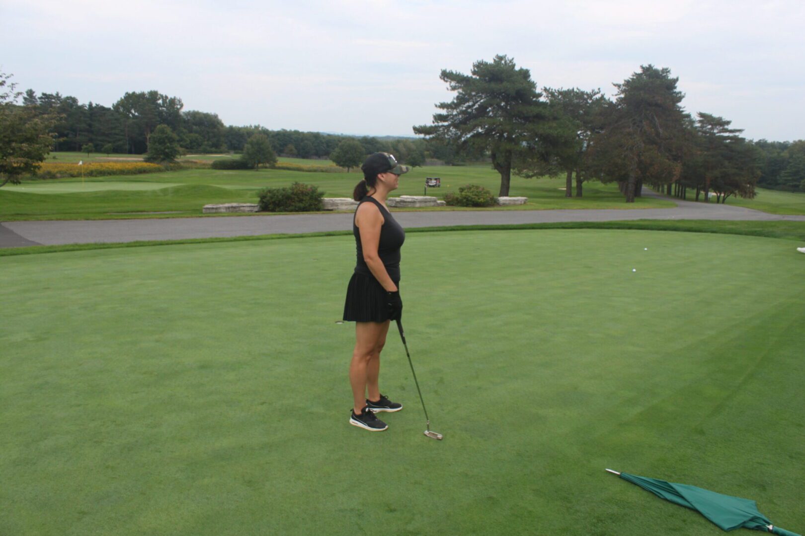 A woman is standing on a golf course.
