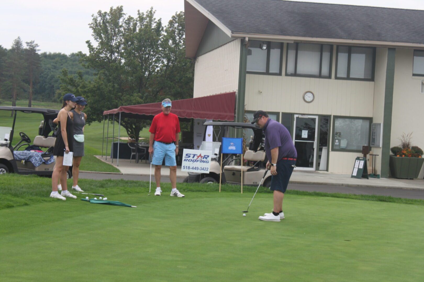 A group of people standing on a golf course.