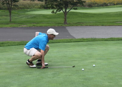 A man crouching down on a golf course.